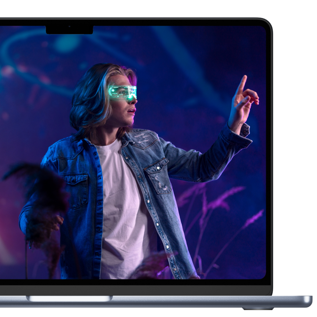 MacBook Screen mit Bild. Bild zeigt einen jungen Mann mit digitaler Brille. Er versucht etwas im virtuellen Raum anzuklicken. Steuerberatung Gen x